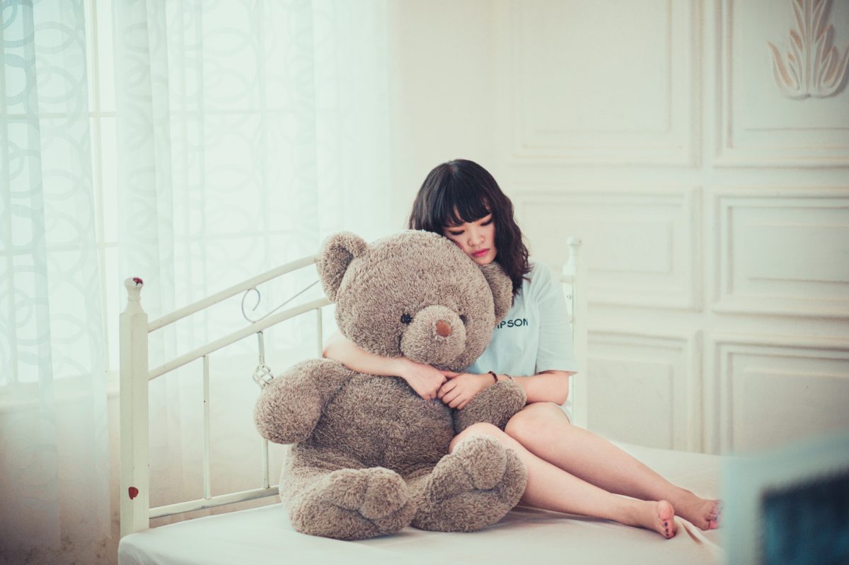 foto de menina segurando um urso triste